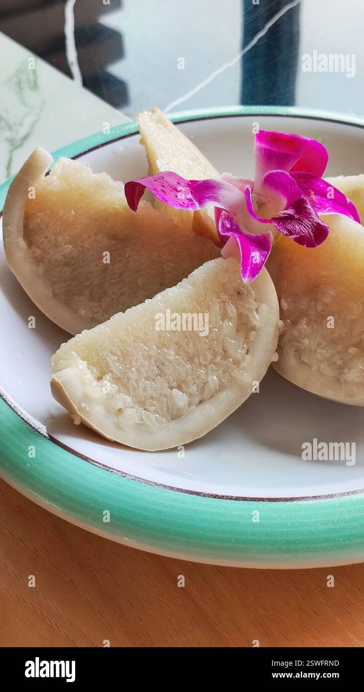 Coconut rice is a local specialty dessert of Hainan, which is also called 'coconut boat'. Coconut shell with glutinous rice and dried coconut flakes Stock Photo