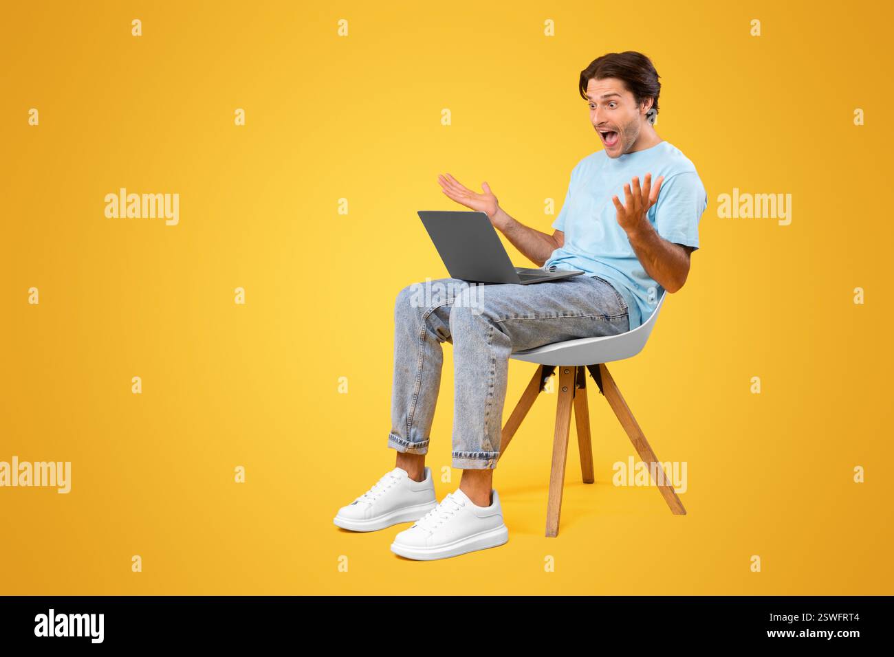 Excited guy using laptop celebrating success sitting on chair Stock Photo