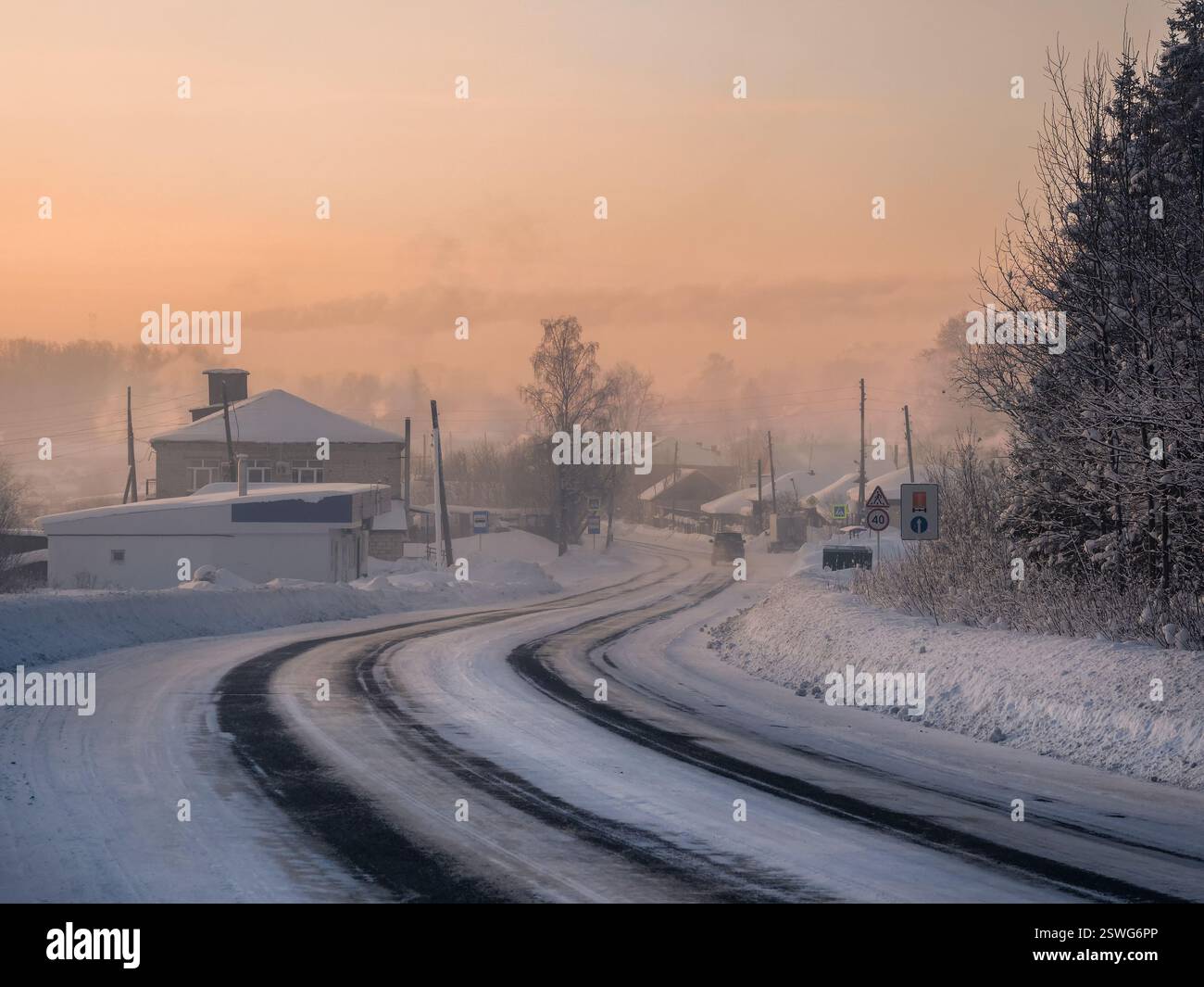 Frosty morning sunrise winter snow-covered highway through Cherdyn village Stock Photo