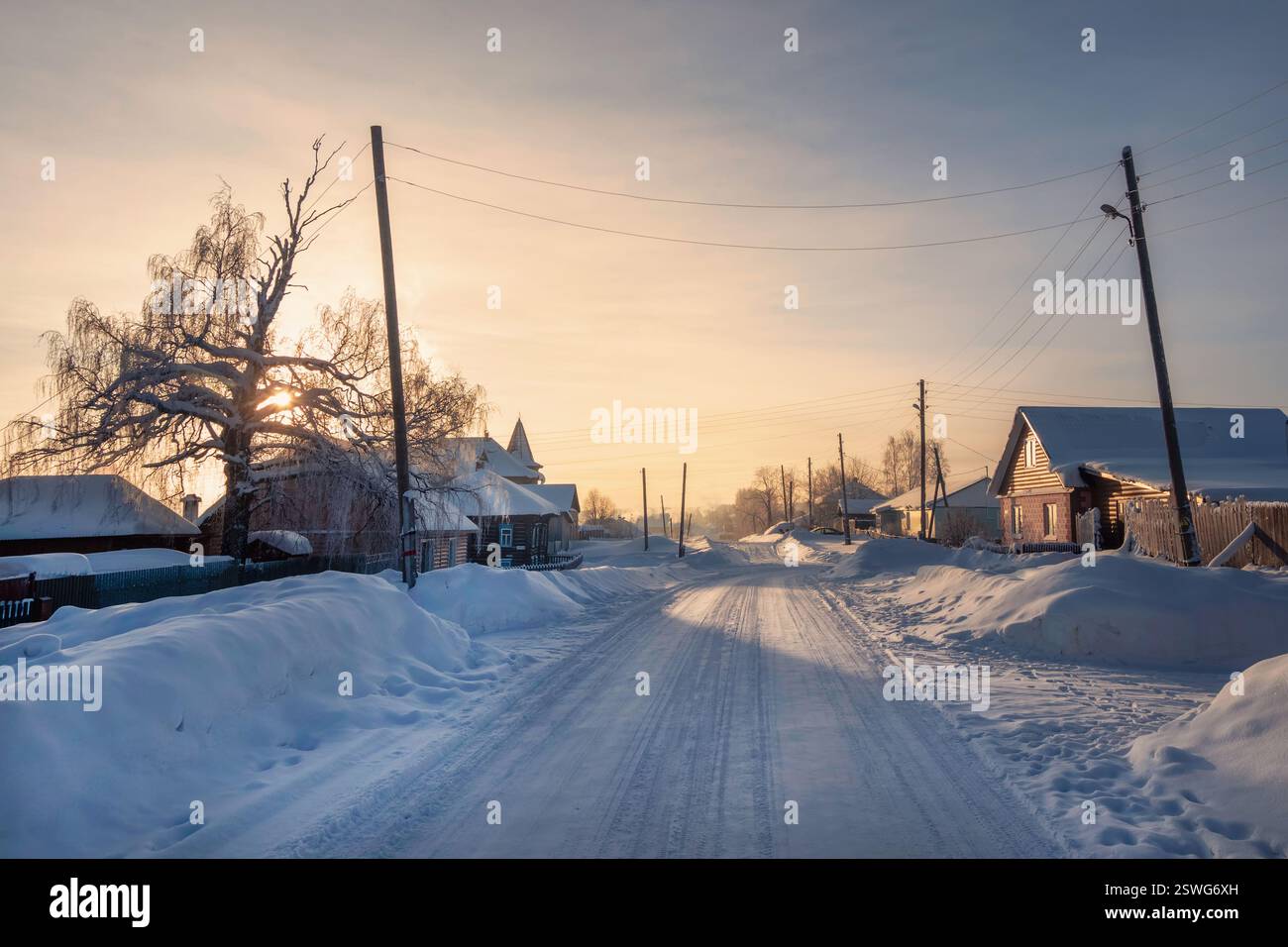 Winter road through a snow-covered village, severe frost, snow haze. Stock Photo