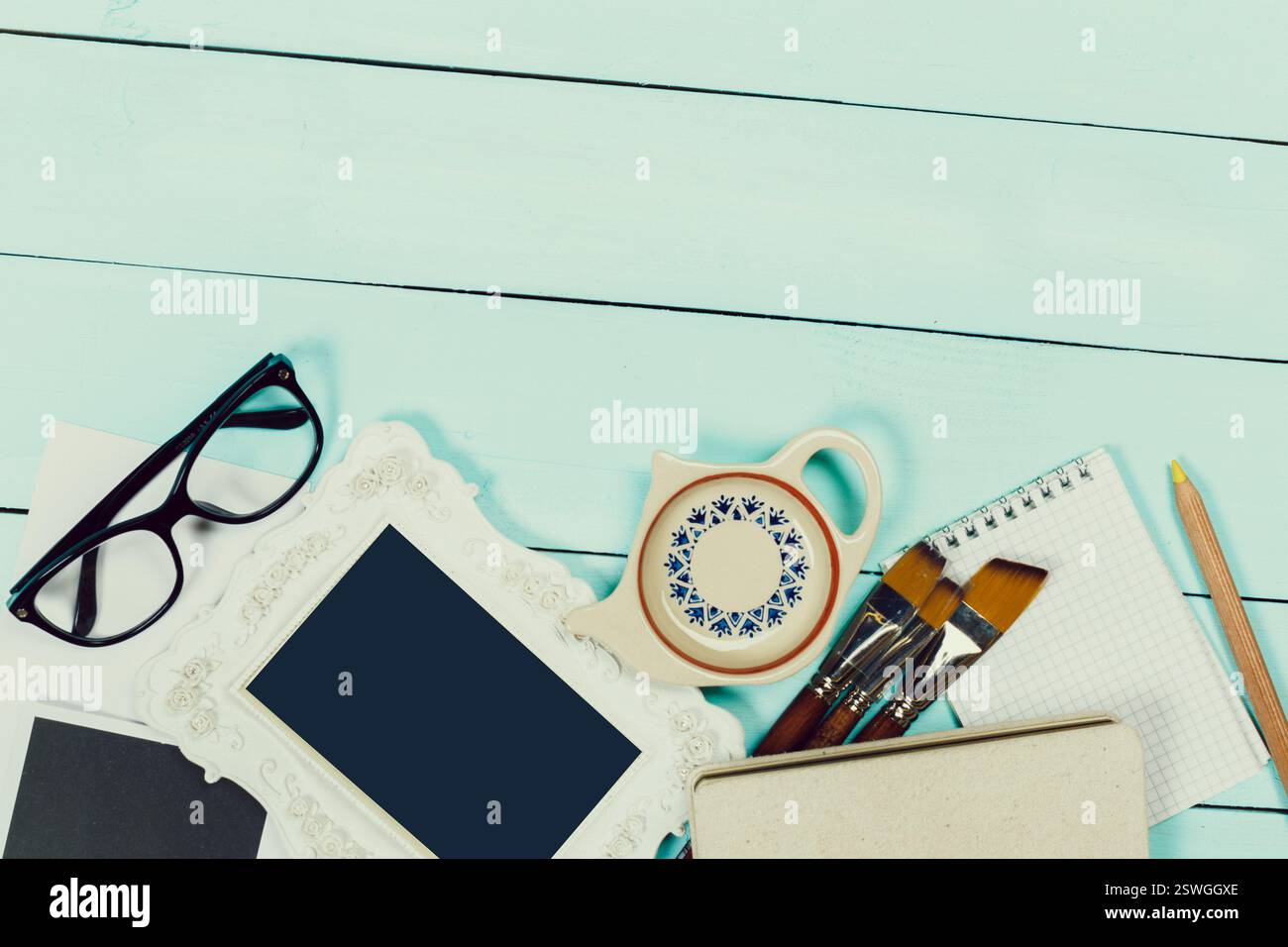Creative workspace setup featuring tools, stationery, and decorative items on a light blue wooden surface Stock Photo