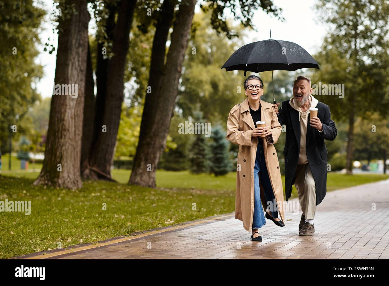 Couple laughs together under an umbrella while walking in the rainy ...