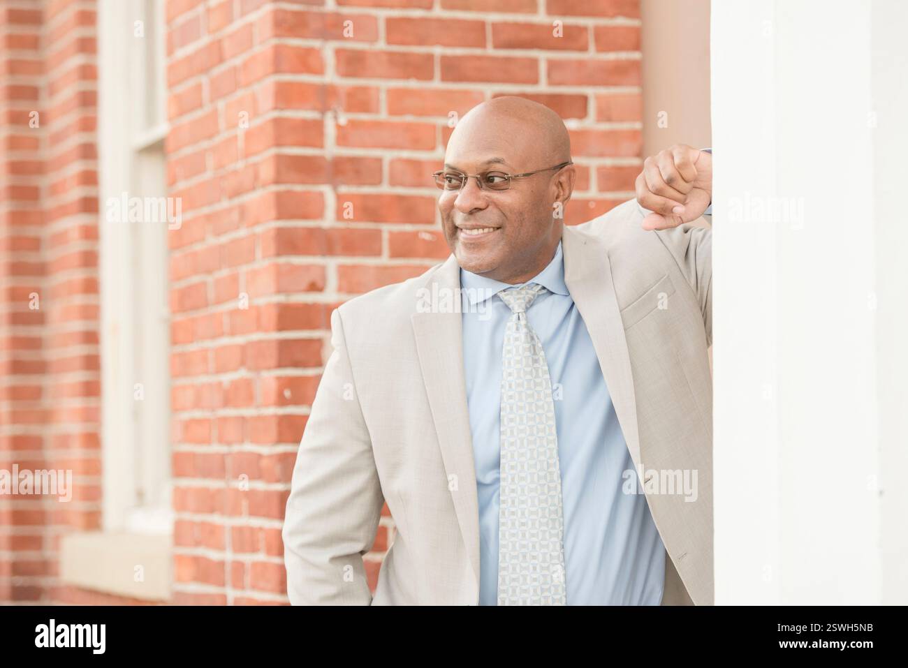 Professional man leaning against wall and smiling Stock Photo - Alamy