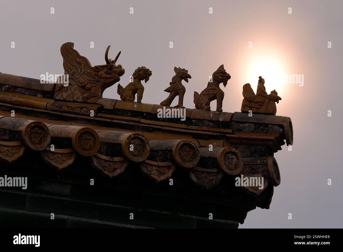 The sun is seen during a cloudy day near mythical creatures decorating ...