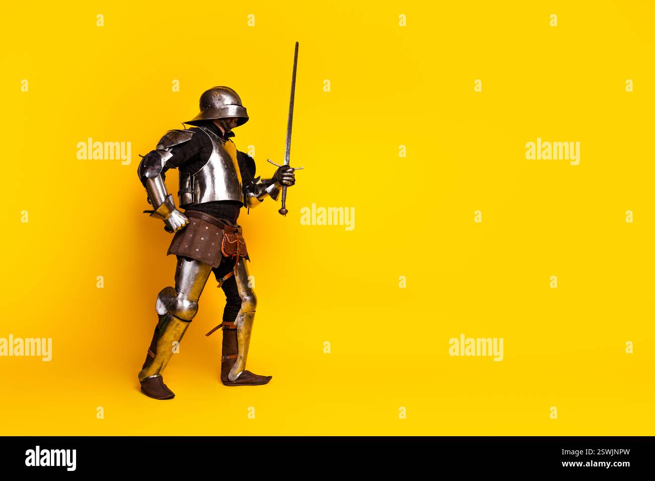 Medieval knight in full armor holding a sword with vibrant yellow ...