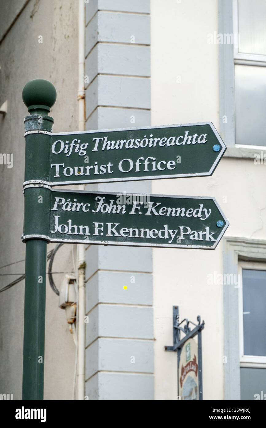 Irish Direction Sign In Cobh Ireland, To The Tourist Office And John F. Kennedy Park, Sign Painted In Irish Green And Bilingual Stock Photo
