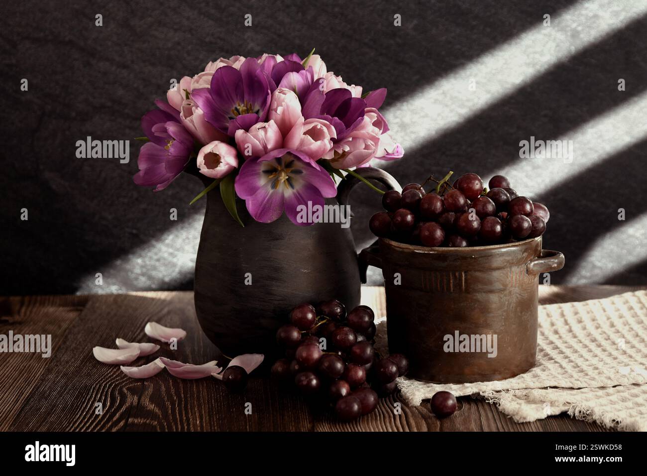 The photograph shows a still life with a bouquet of tulips and grapes ...