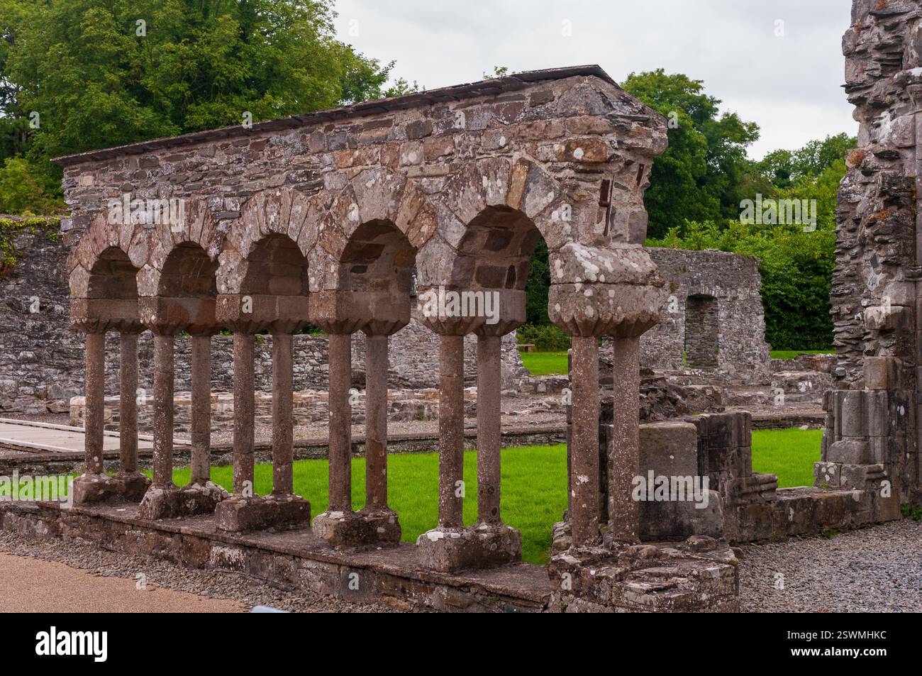 The arched stone pillars are part of a building that is surrounded by grass. The pillars are tall and narrow, and they are arranged in a row. The buil Stock Photo