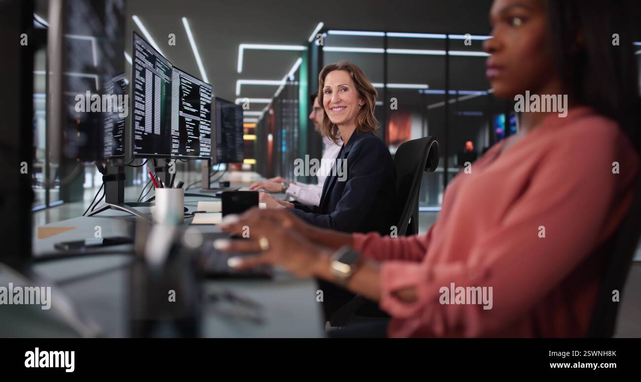 African American coder happily coding on desktop in diverse office. Stock Photo