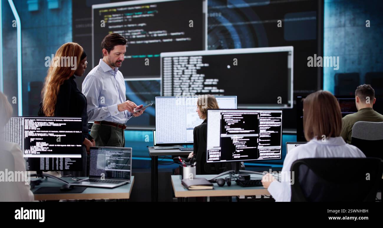 Team of diverse software engineers coding on desktop computers in office. Stock Photo