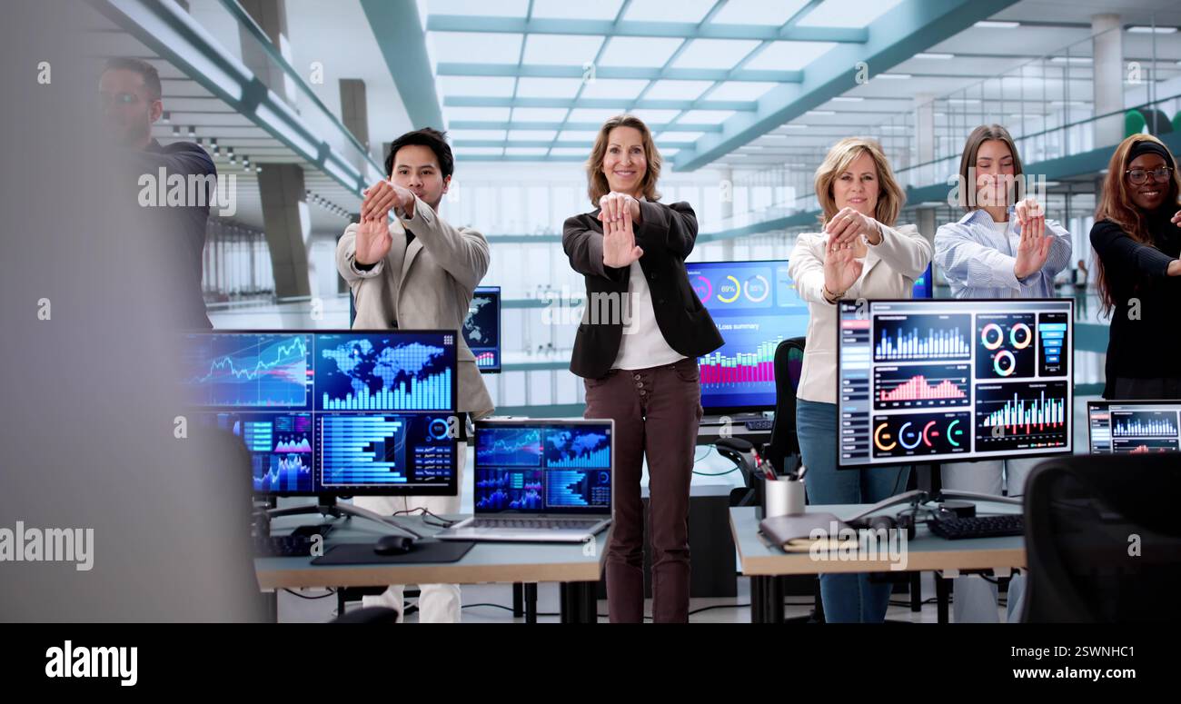 Office workers from different backgrounds practicing yoga at their desks. Stock Photo