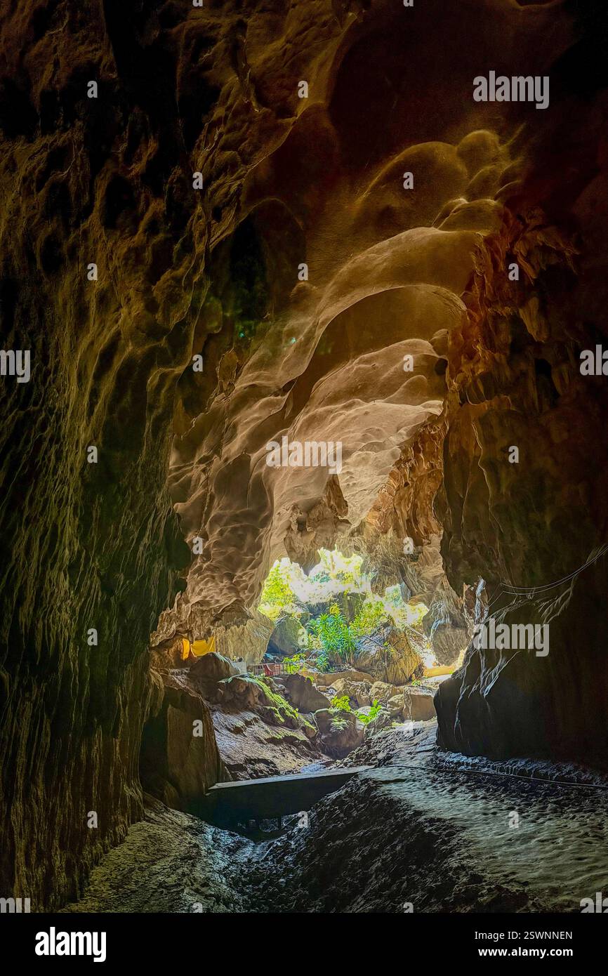 Entrance of a Cave Illuminated by Natural Light A breathtaking view from inside a cave, showcasing rock formations shaped by erosion. Sunlight filters - Smartphone Captured Stock Image