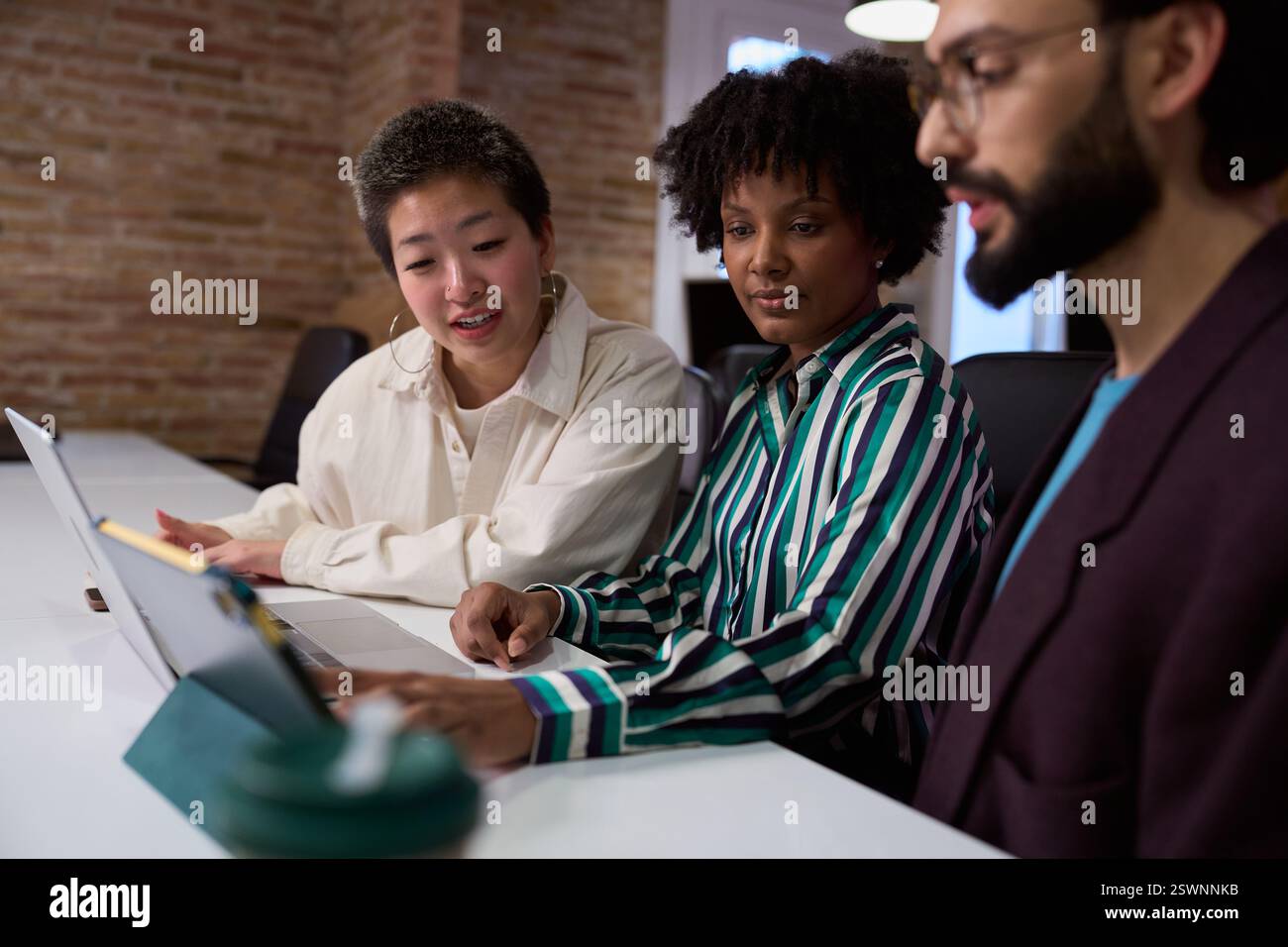 Marketing team working on project using laptop and tablet Stock Photo