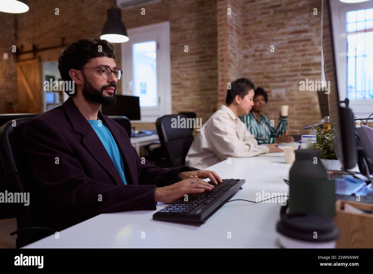 Focused employee typing on keyboard in busy office Stock Photo