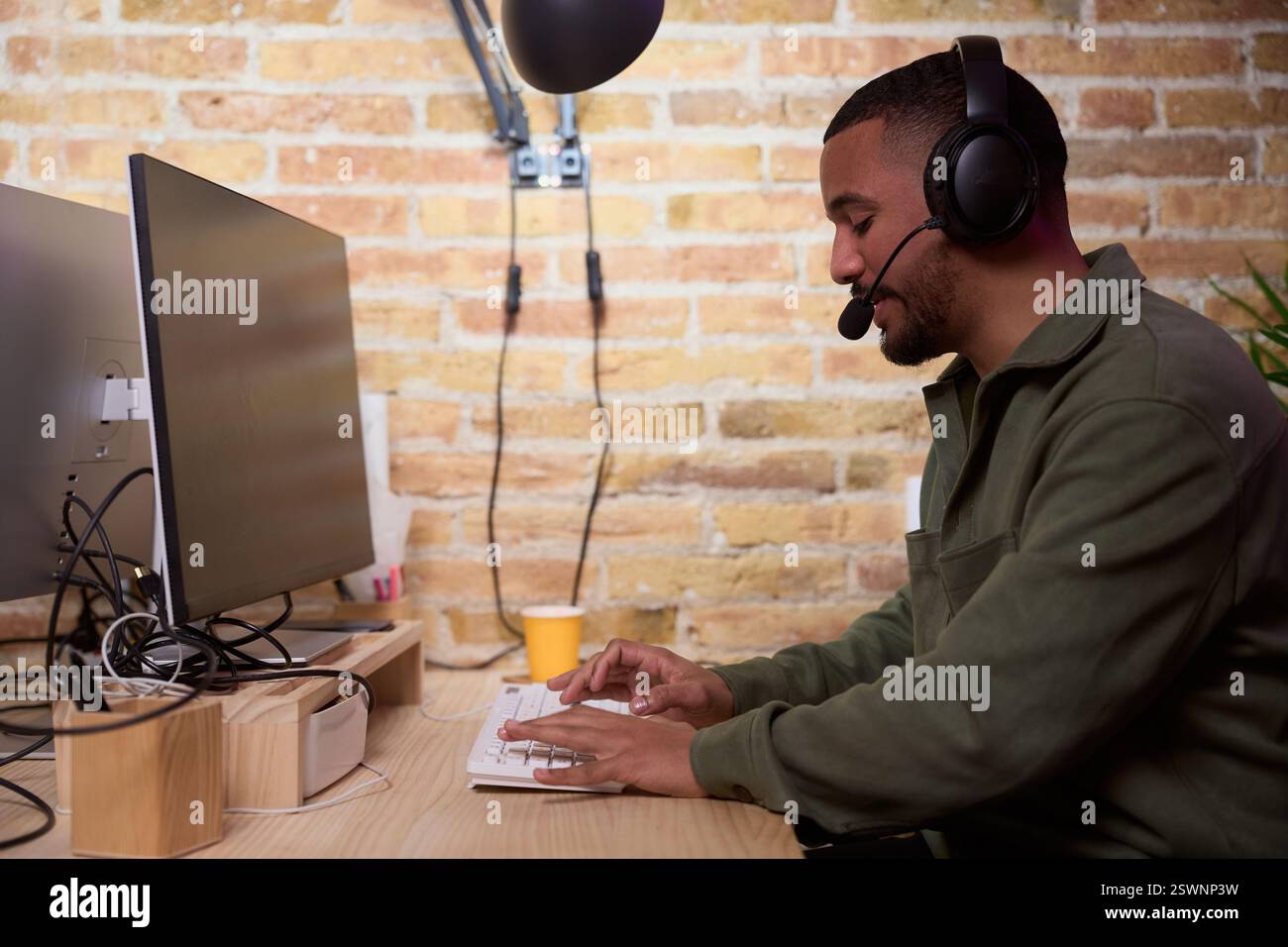 Focused programmer working on computer wearing headset in modern office Stock Photo