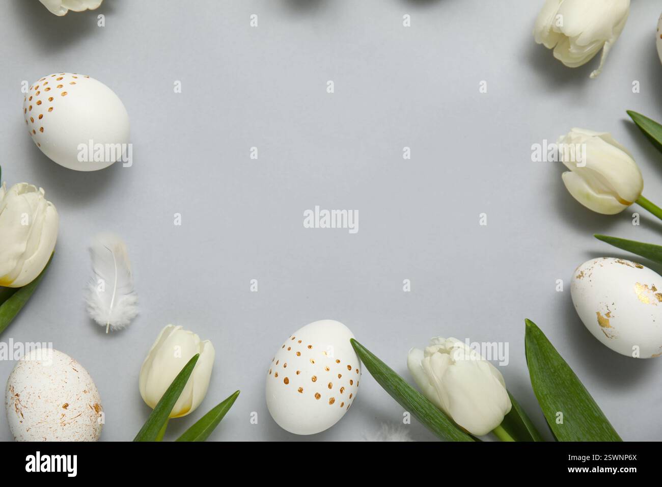 Frame made of tulips with Easter eggs and feathers on white background ...