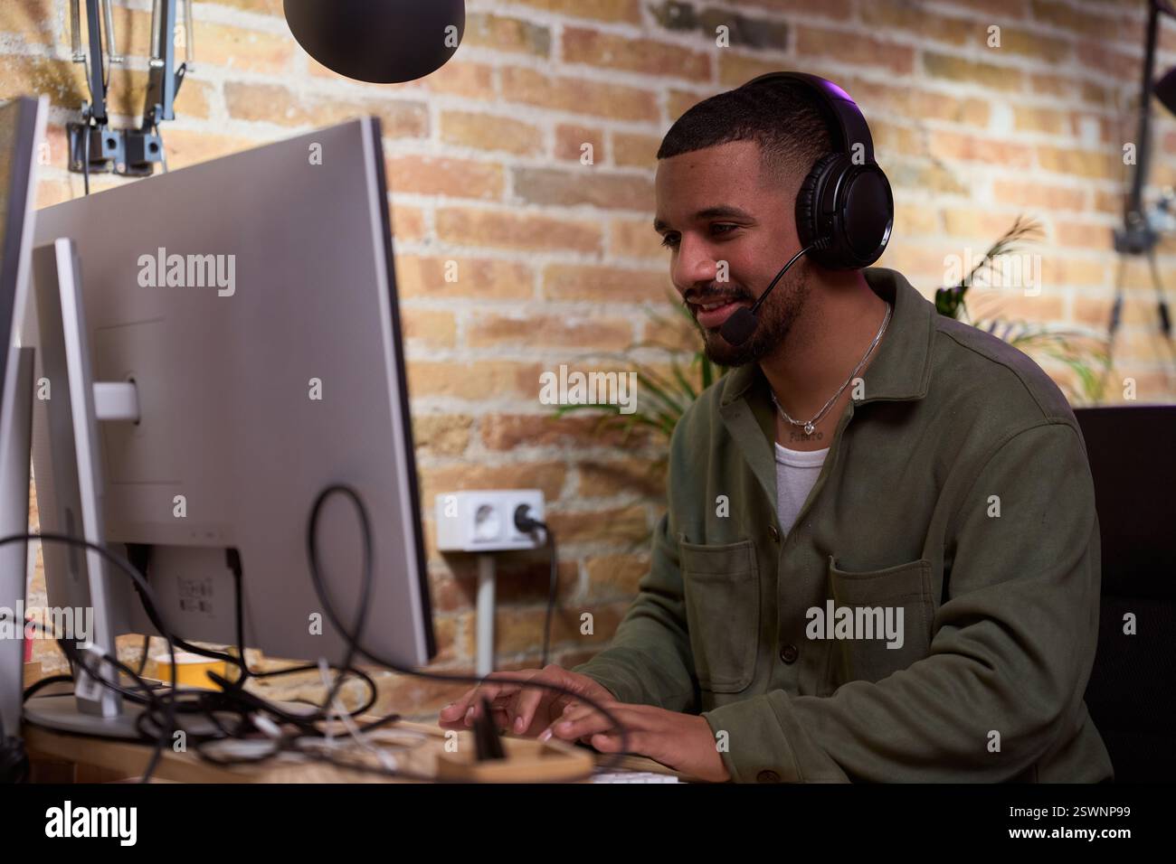 Focused young businessman working from home using computer and headset Stock Photo