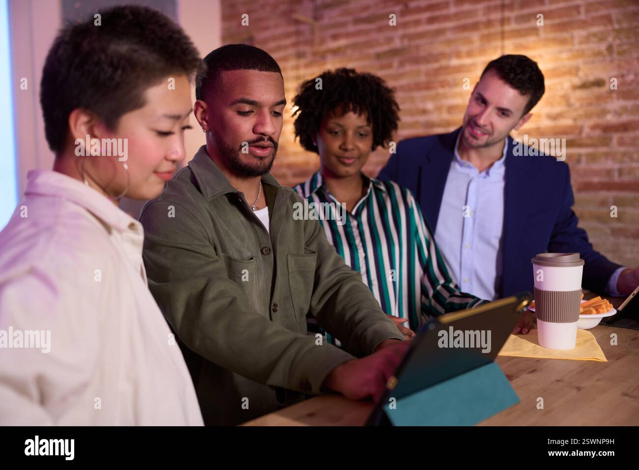 Creative team using tablet, discussing project in cafe Stock Photo
