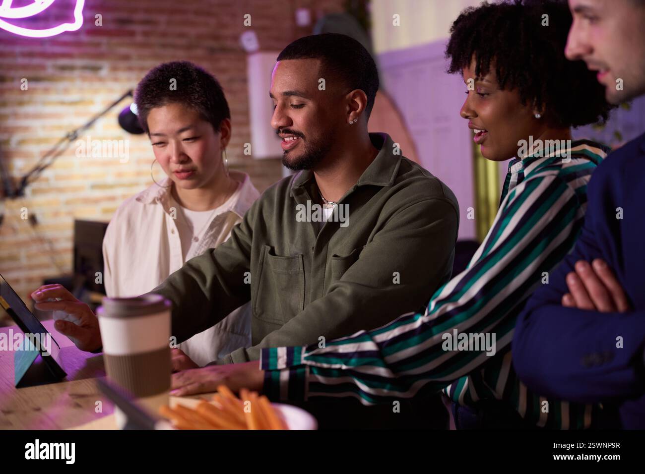 Diverse team collaborating on digital tablet in modern office Stock Photo