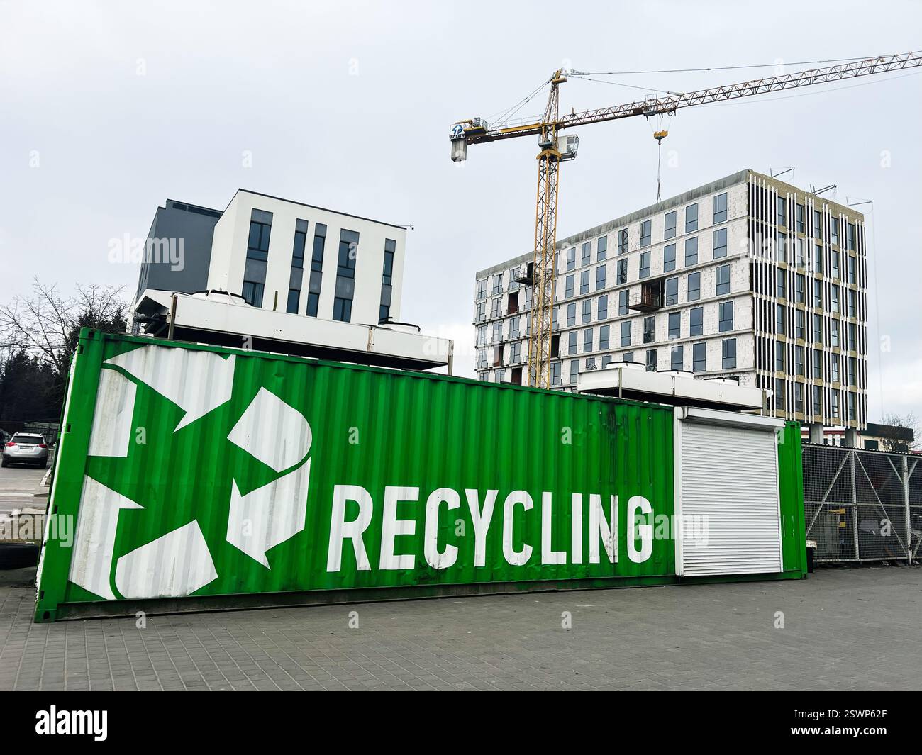 Green recycling container near modern urban buildings and construction ...