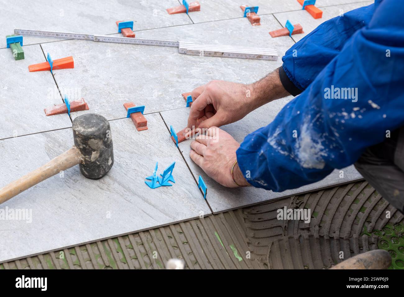 Bricklayer tiler installs tiles using leveling spacers. Construction industry. Building. Stock Photo