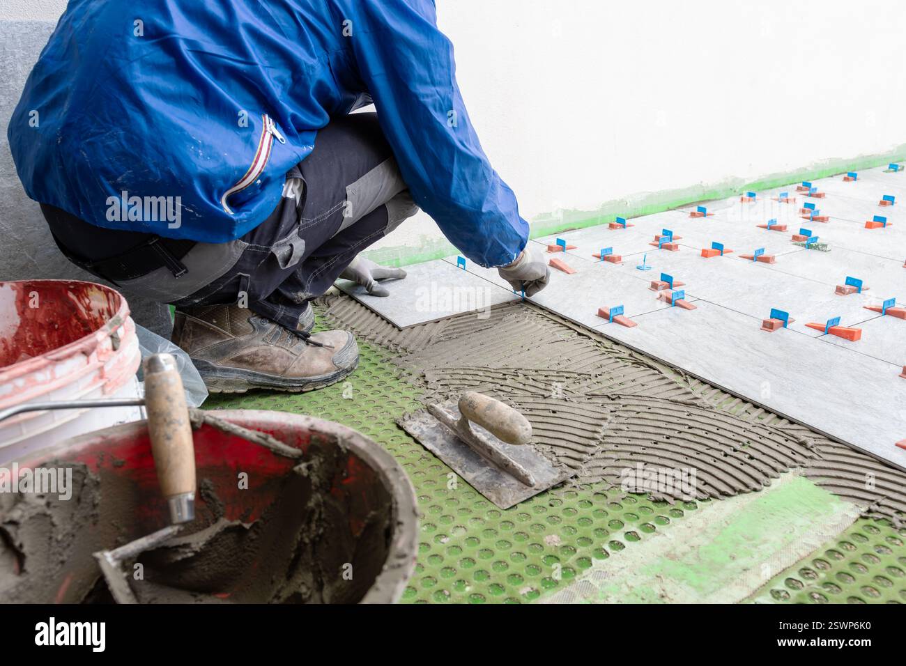 Bricklayer tiler installs tiles using leveling spacers. Construction industry. Building. Stock Photo