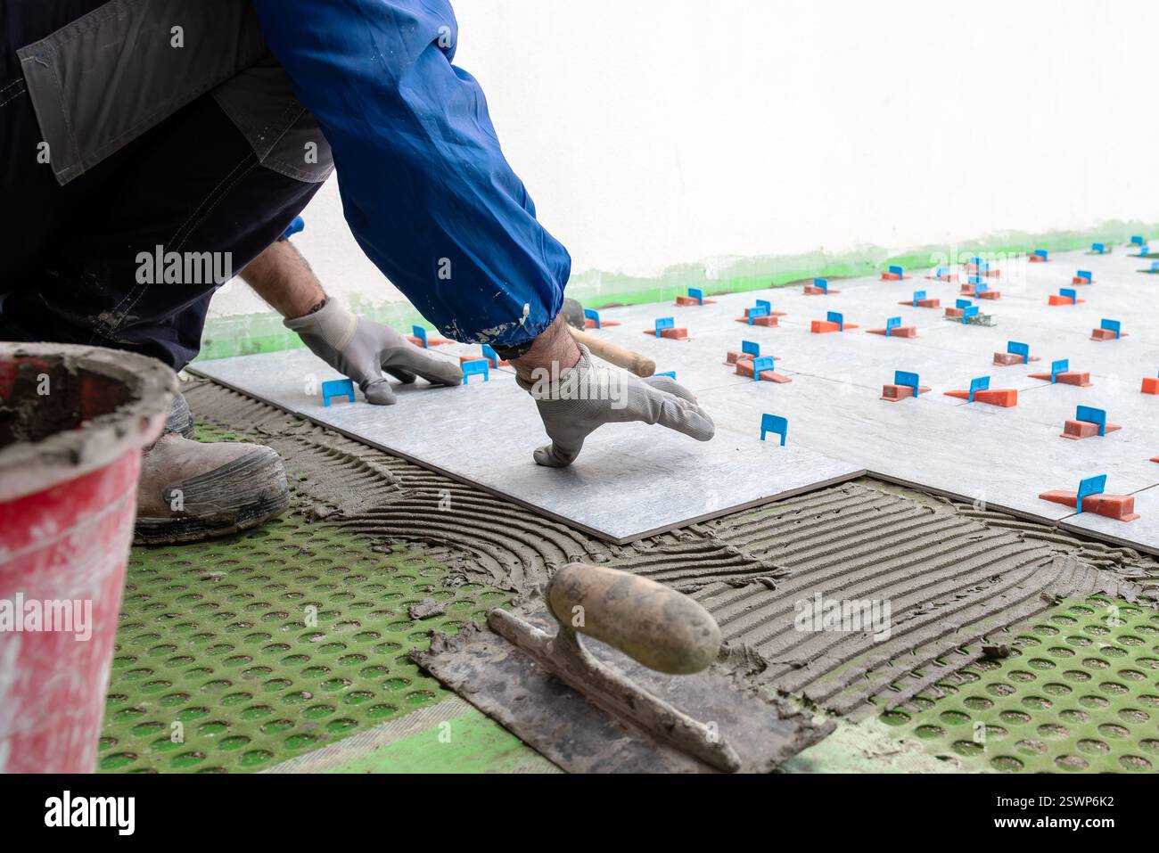 Bricklayer tiler installs tiles using leveling spacers. Construction industry. Building. Stock Photo