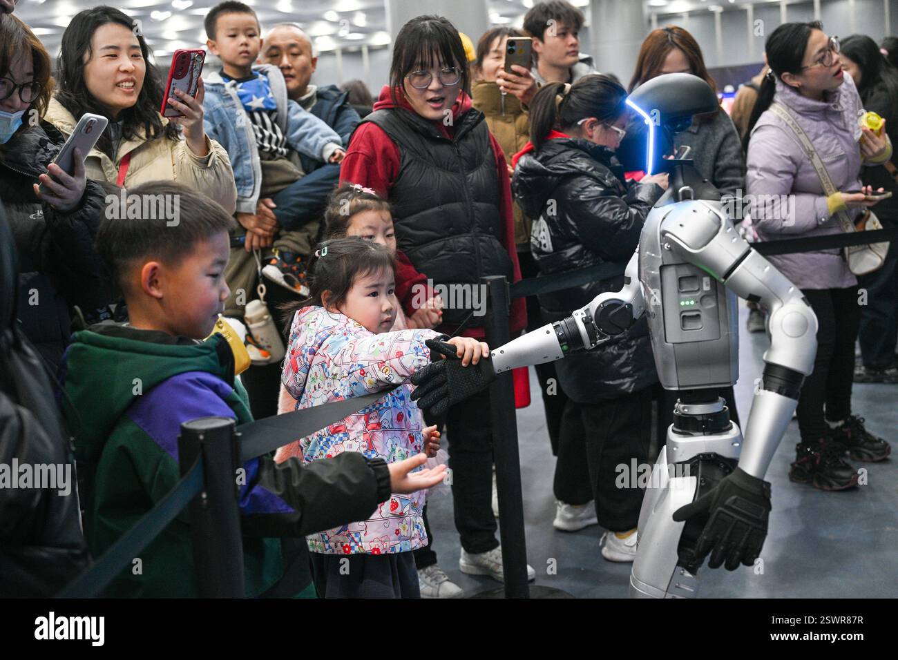 NANJING, CHINA - FEBRUARY 22, 2025 - A child shakes hands with a robot ...