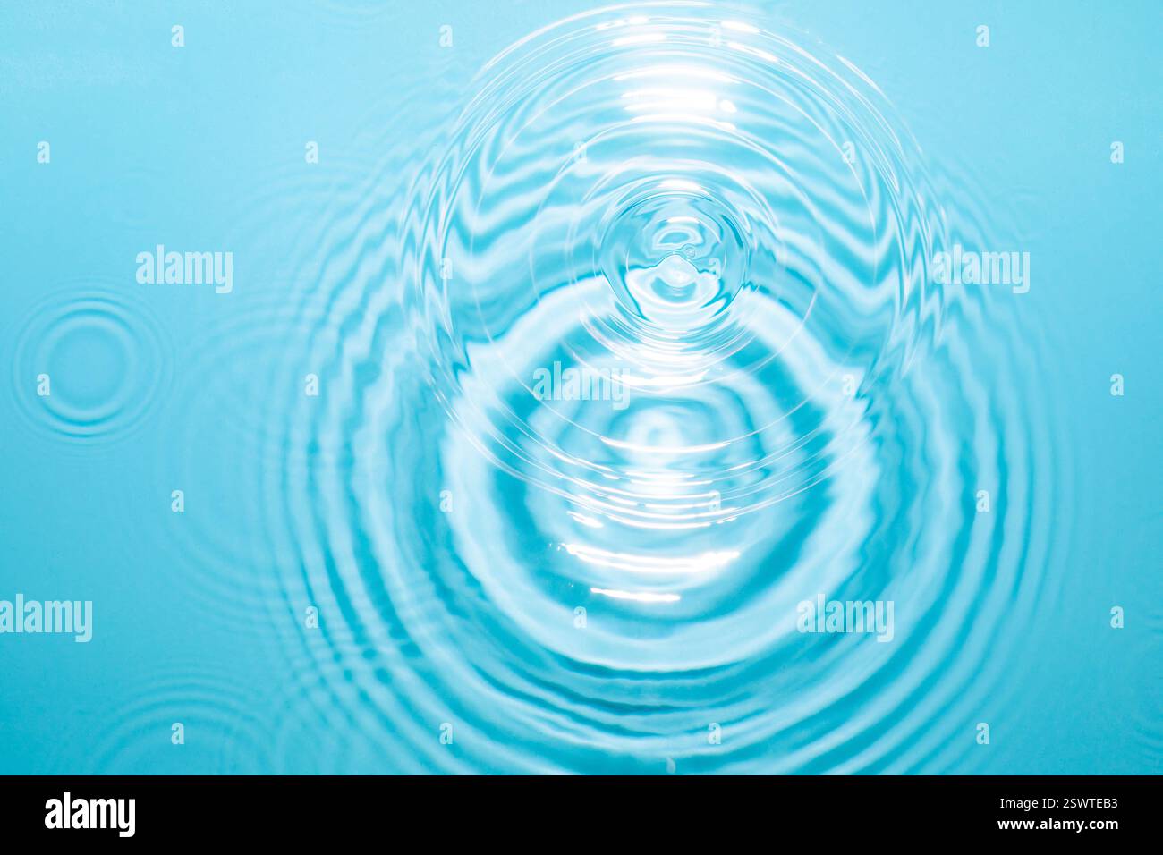 Water ripples expand in serene blue water. Texture. Background. Stock Photo