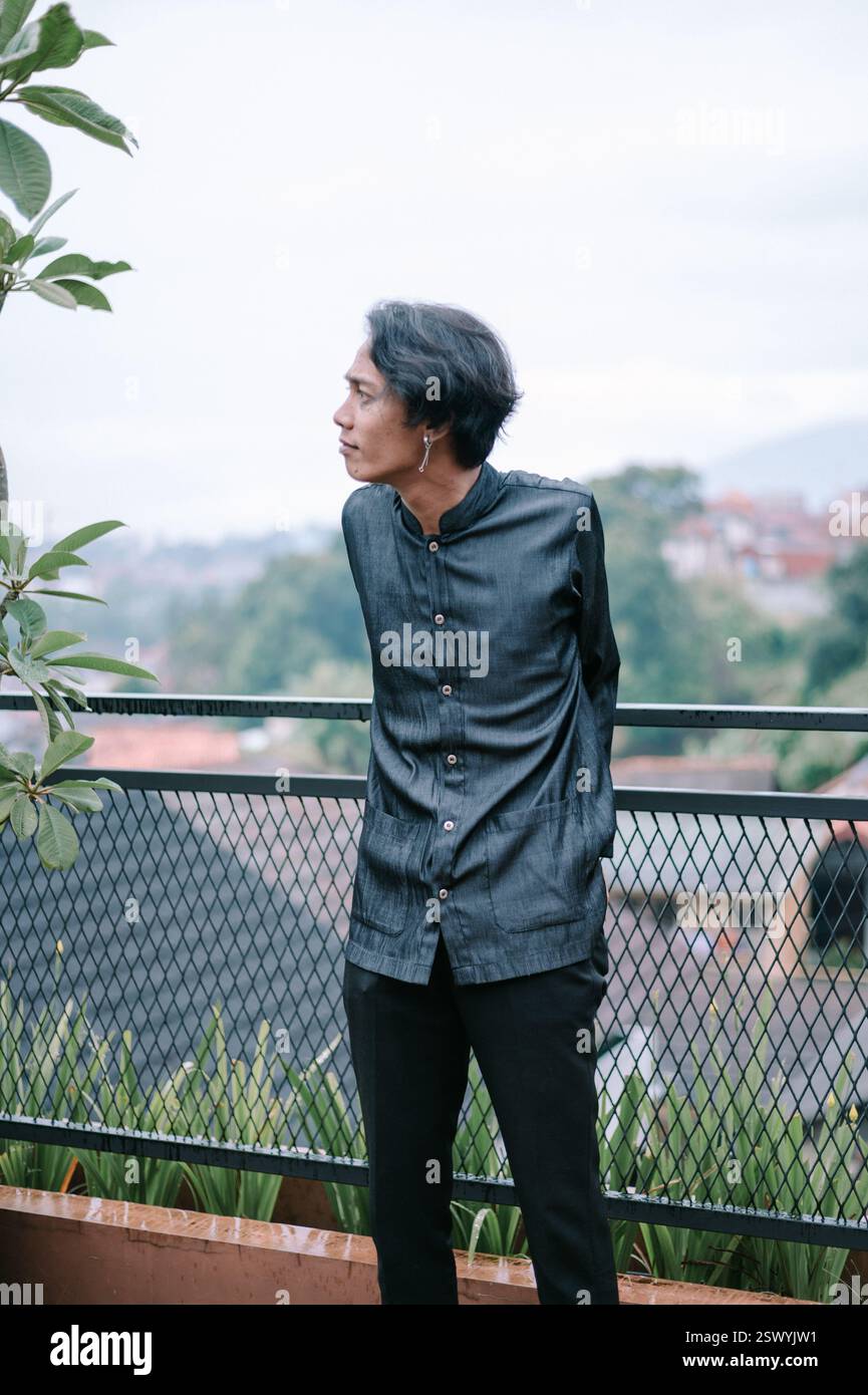 A stylish young man looks thoughtfully out over a green landscape from ...