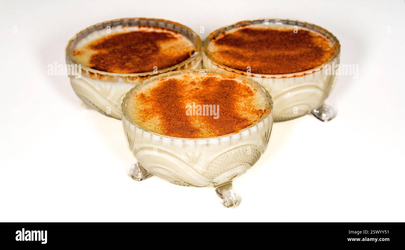 Traditional Turkish Rice Pudding in Elegant Vintage Glass Bowls with a Dusting of Cinnamon on a White Surface in a Classic Dessert Presentation Stock Photo