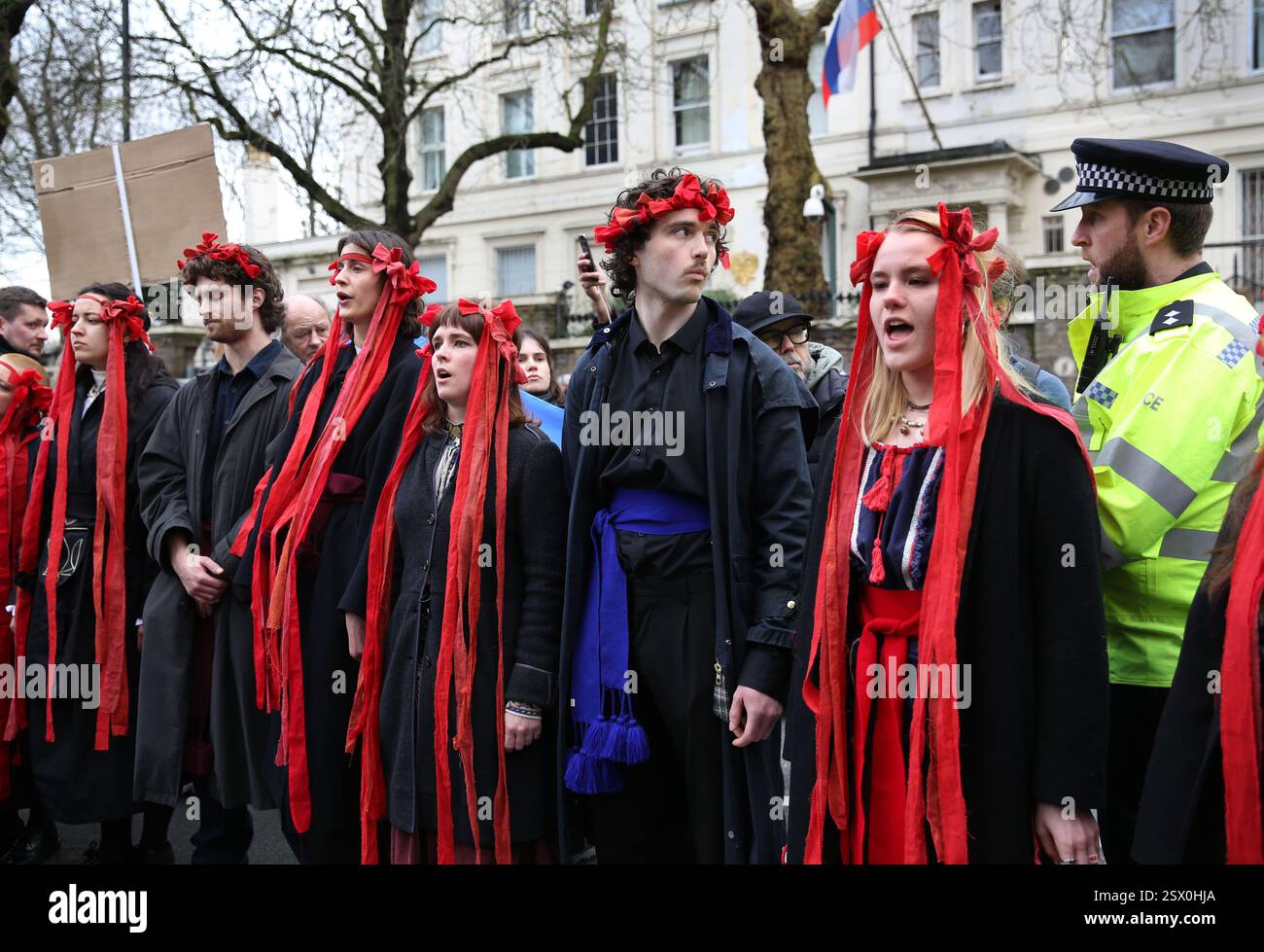 London, England, UK. 22nd Feb, 2025. Protesters dressed in red ribbons ...