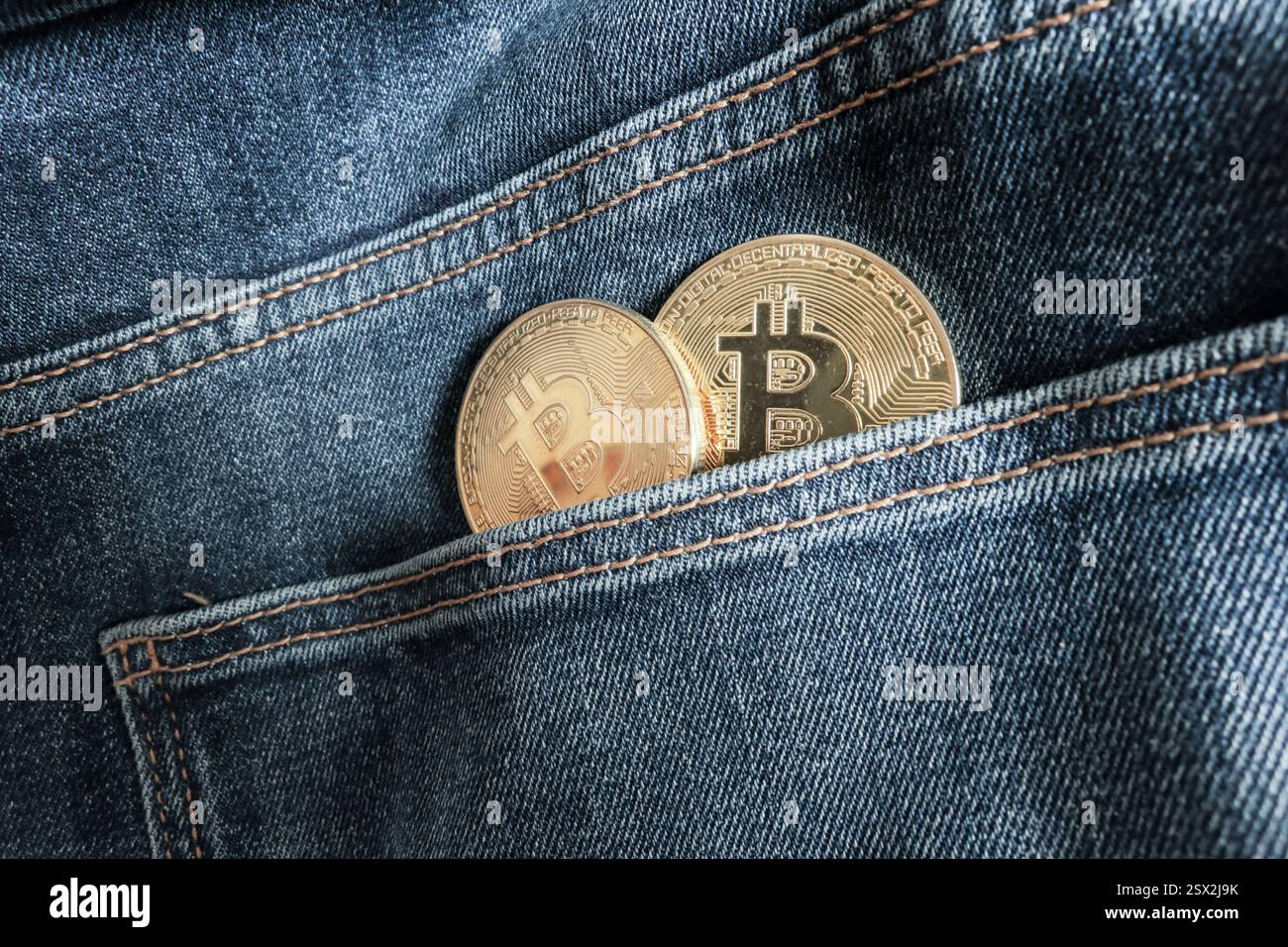 Two Bitcoin physical coins inside a blue jeans pocket Stock Photo