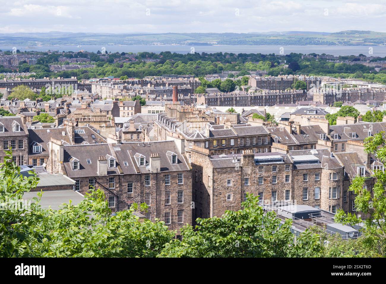 A scenic view of historic buildings in Edinburgh viewed from Calton Hill, UK, with classic stone buildings, rooftops, and lush greenery. Stock Photo