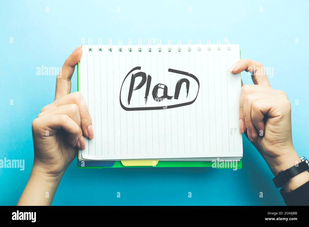 plan text on notepad on woman hand on blue background Stock Photo - Alamy