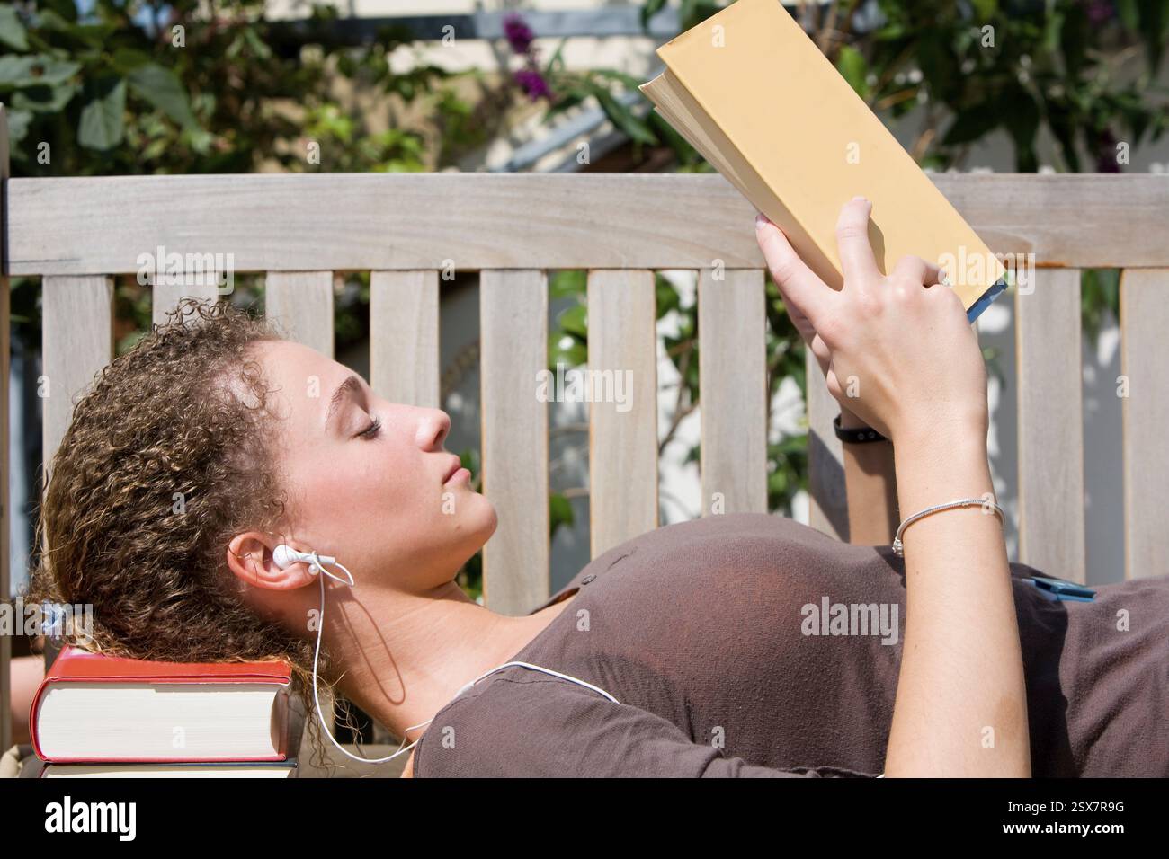 Young woman sits on a bench and reads a book Stock Photo