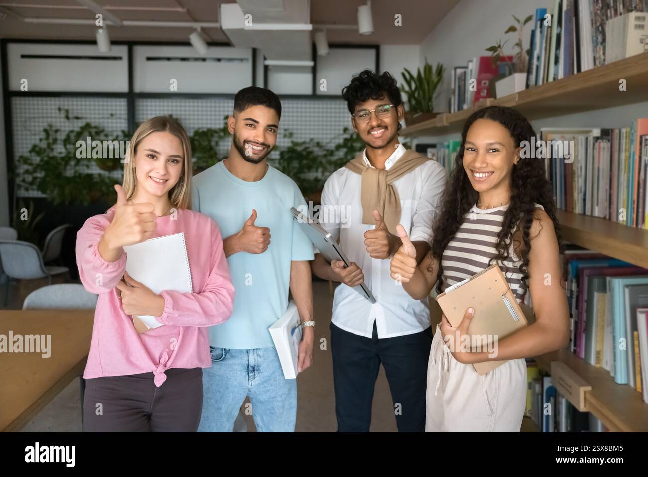 Four multinational students showing thumbs up gesture Stock Photo - Alamy