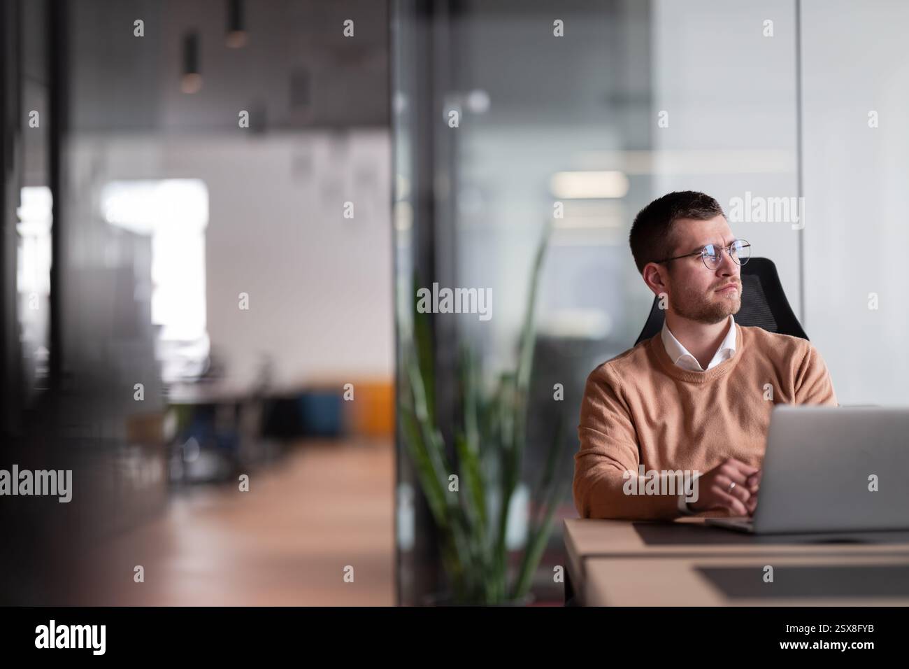 Businessman in glasses distracted from computer work look in distance thinking or pondering, thoughtful biracial male lost in thoughts make plans Stock Photo