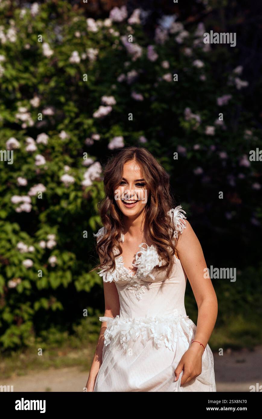 Stunning bride gracefully poses in a spring park, among blossoming trees. exuding elegance, Stock Photo