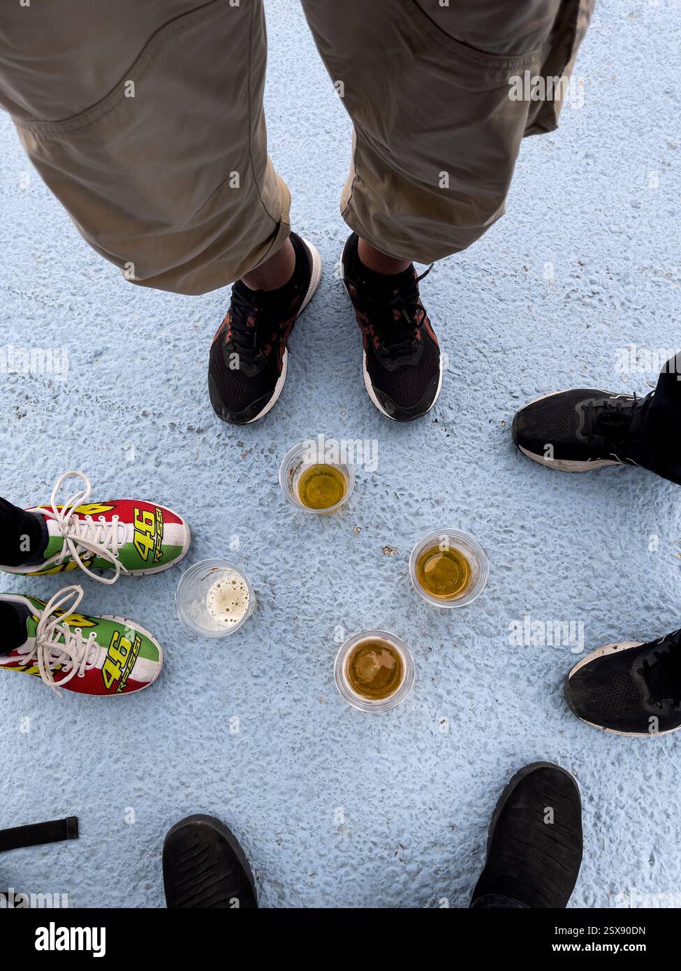 Four people having a beer at Misano track and one wears Valentino Rossi fan shoes - Smartphone Captured Stock Image