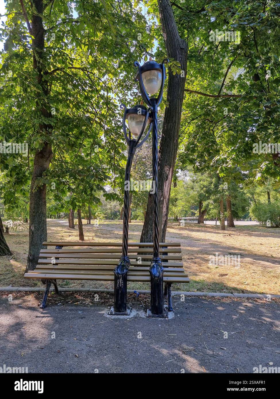 Artwork in park in Odesa / Odessa, Ukraine: 'The Bench of the Lovers' or 'The Lampposts in Love'; two lanterns / street poles sitting on bench - Smartphone Captured Stock Image
