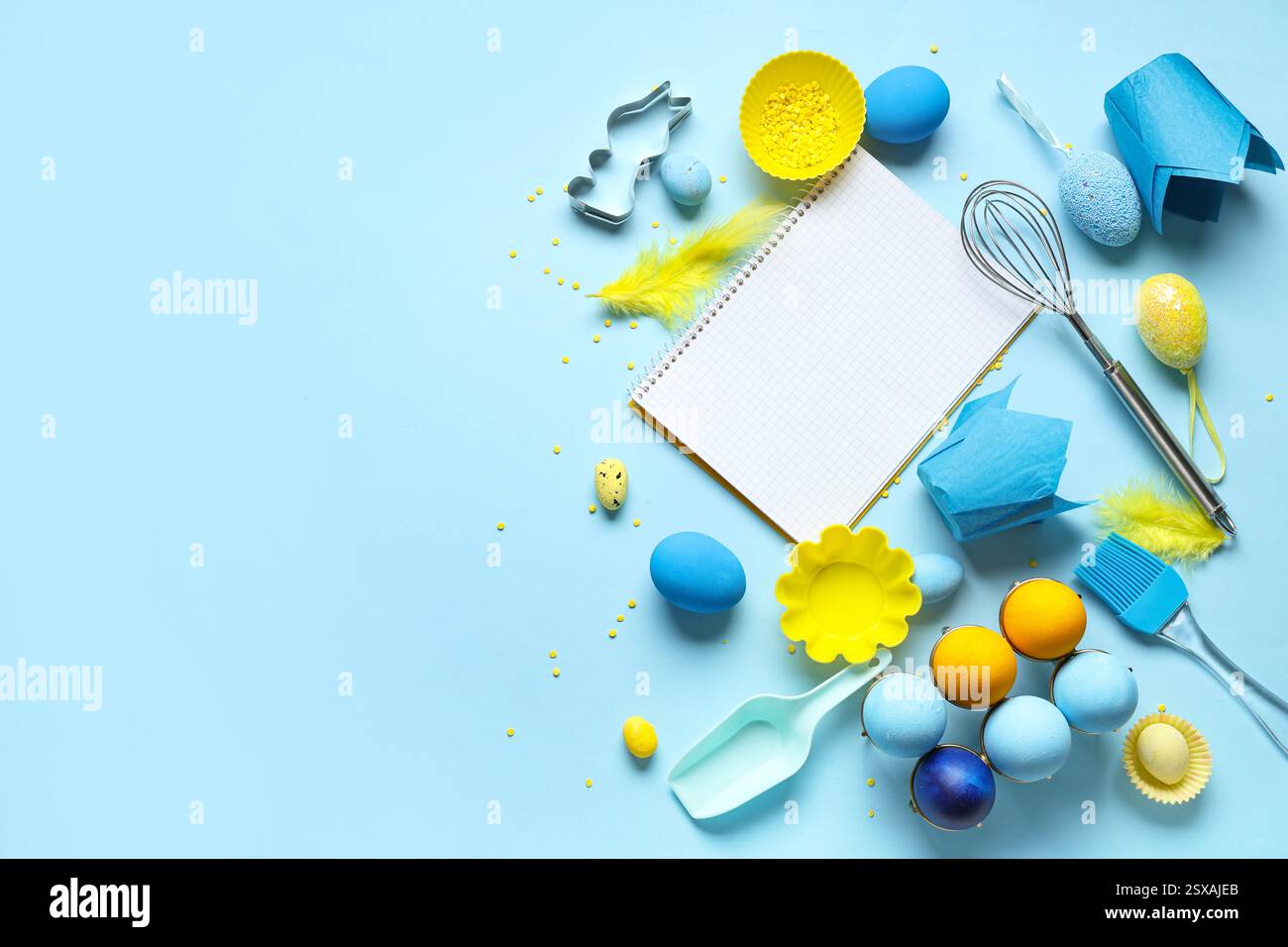 Blank notepad for recipes with baking tools and Easter eggs on blue background Stock Photo