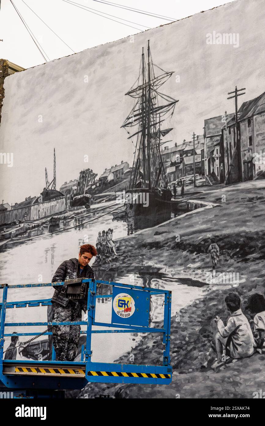 Person working on a historic painting of ships in the harbour, Wicklow, Ireland Stock Photo
