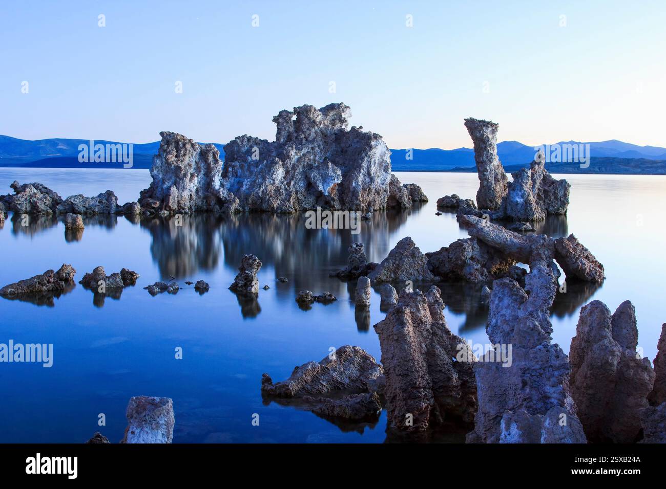 Large rock formation sits on the shore of a lake. The water is calm and ...