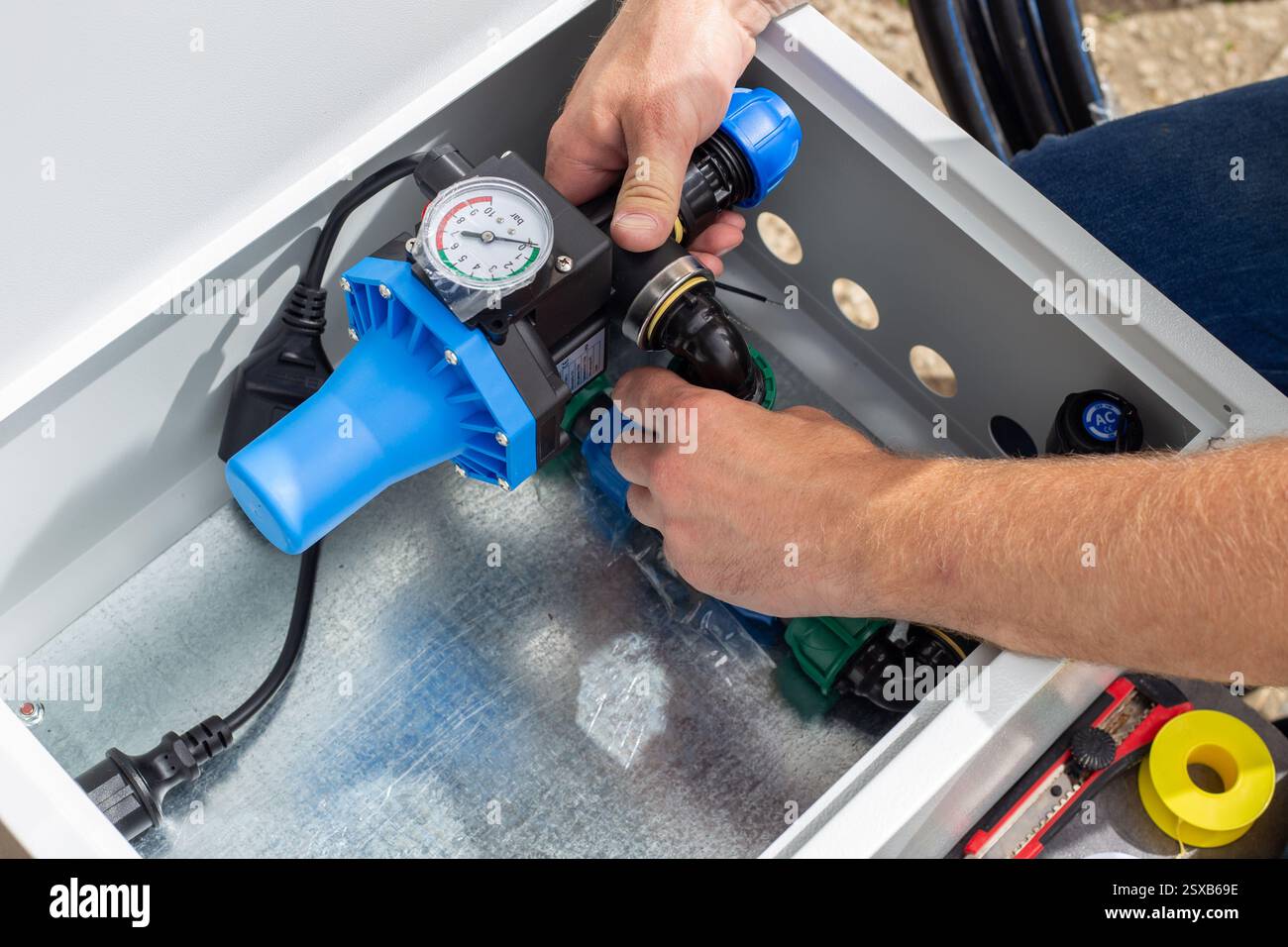 installation of the automatic control unit of the drip irrigation system, arrangement of the automatic control unit elements in a metal box. Stock Photo