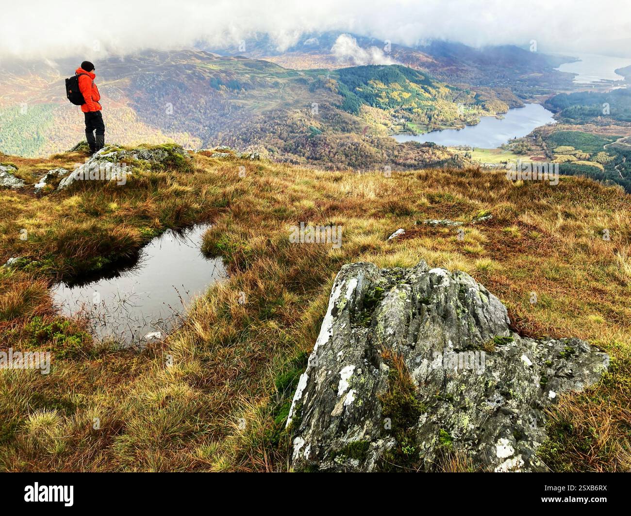 Hiker on the summit of Ben Venue with a view towards Loch Achray and Loch Venacher, The Trossachs, Scotland - Smartphone Captured Stock Image