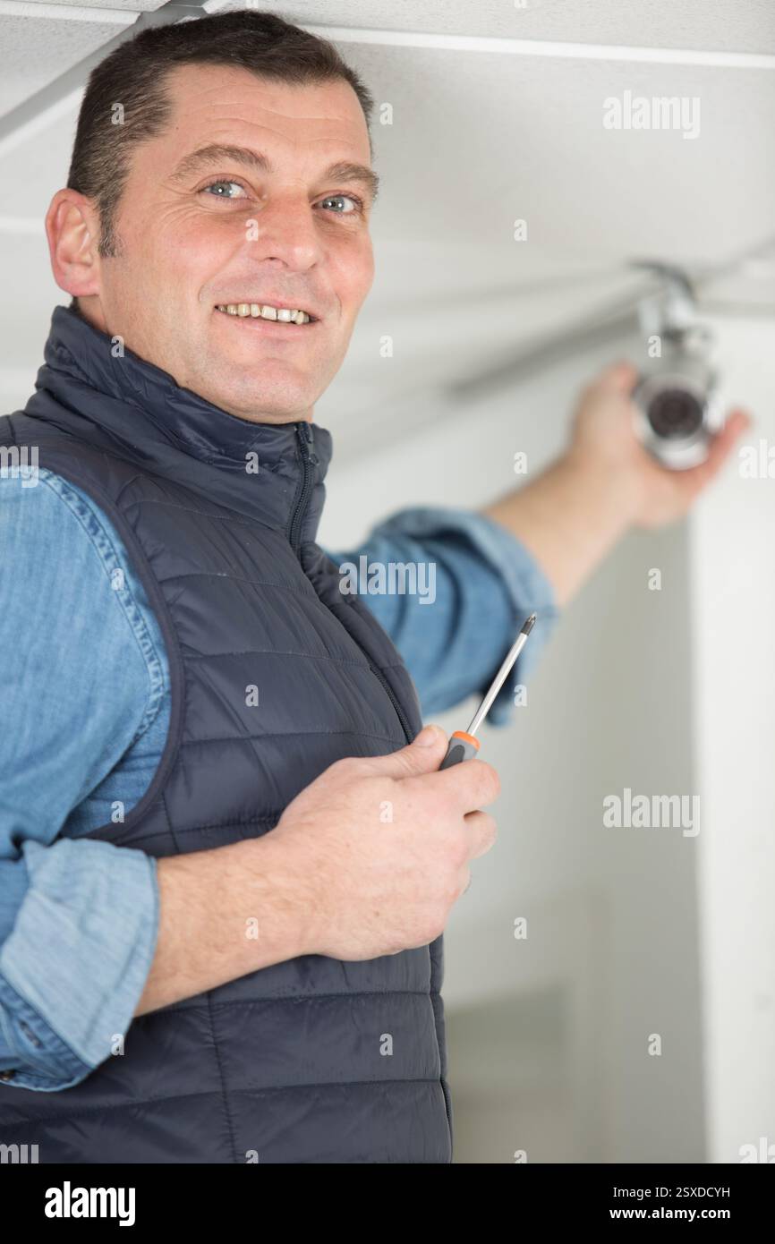 handyman installing security camera on the ceiling Stock Photo