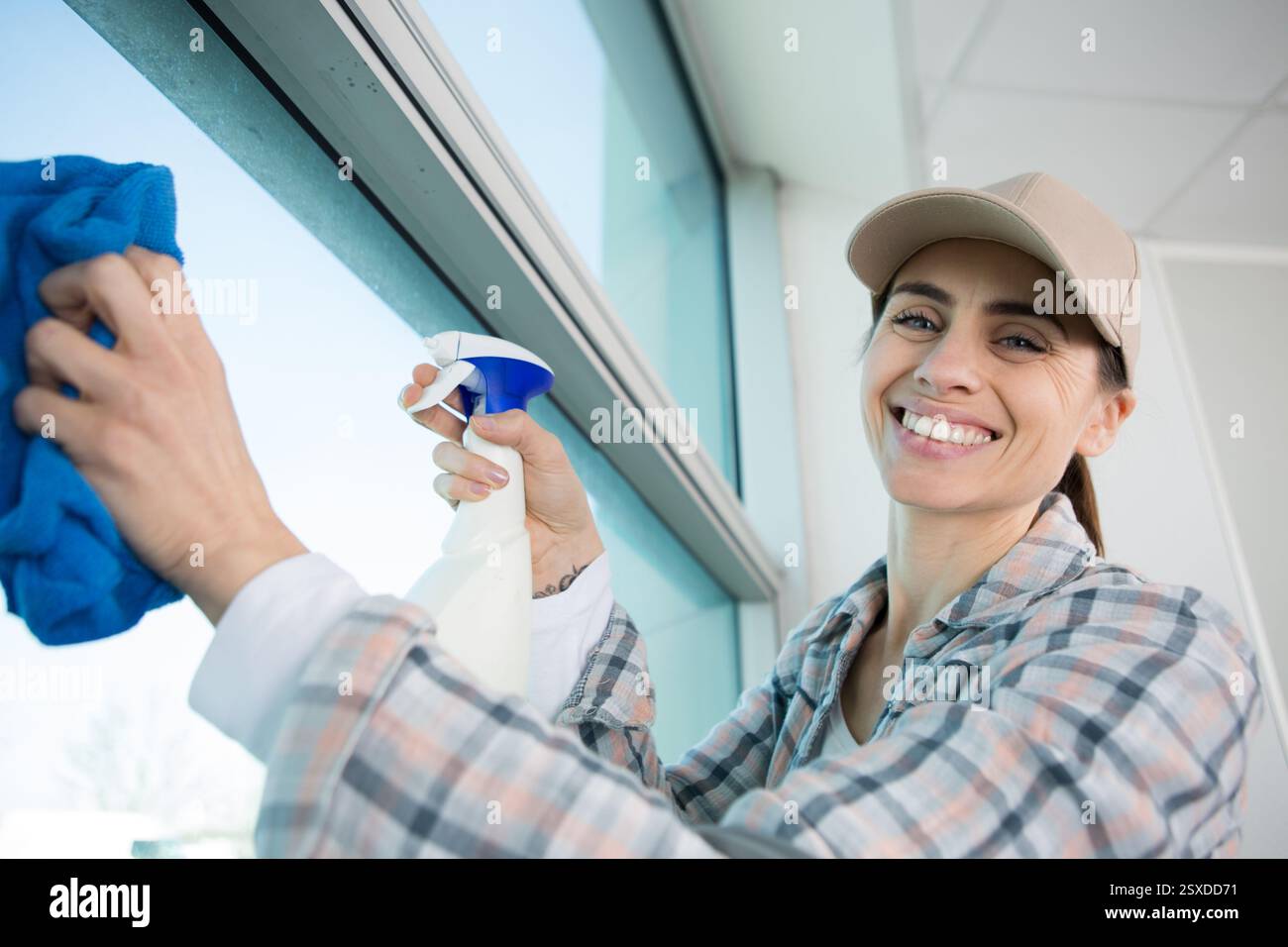 smiling professional woman cleaning windows Stock Photo