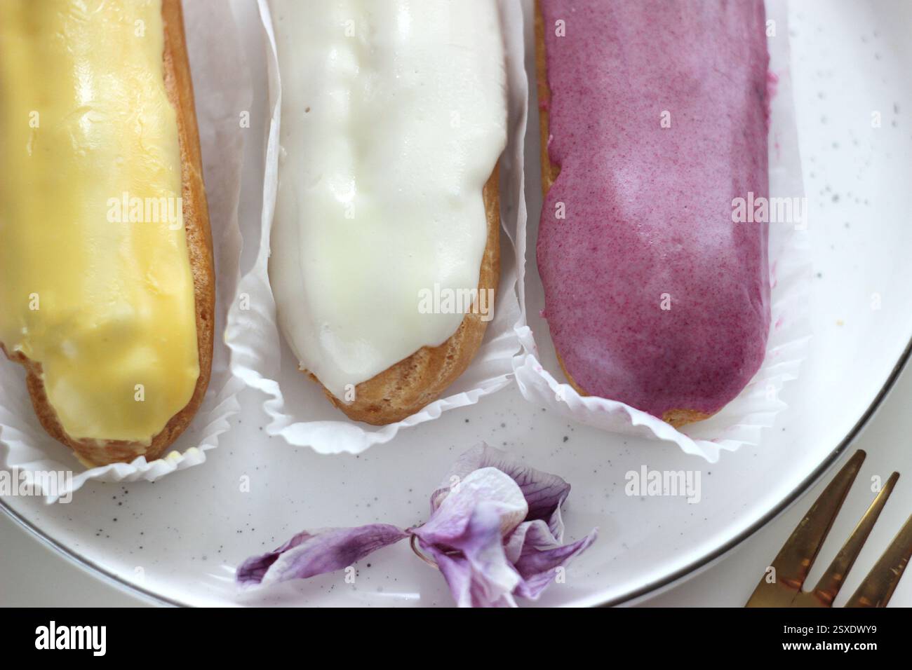 Three eclairs with different fillings lie in a plate Stock Photo