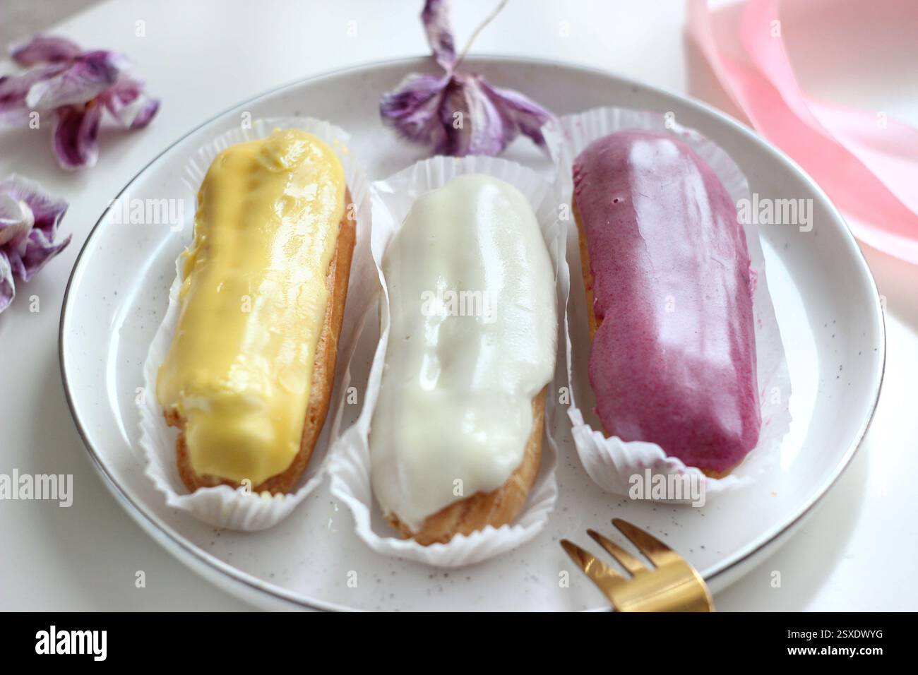 Three eclairs with different fillings lie in a plate Stock Photo